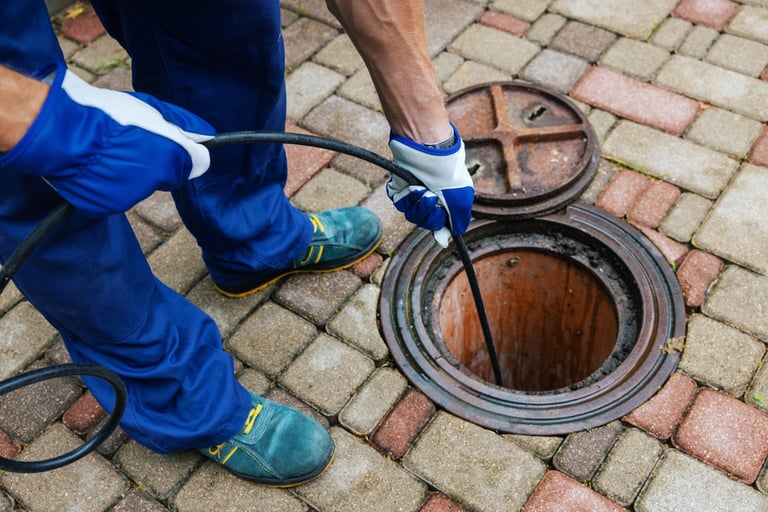 Professional plumber using hydro jetting to clean a clogged drainage pipe