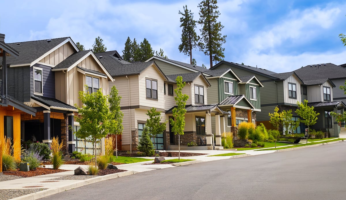 A quiet neighborhood street with homes under a clear blue sky