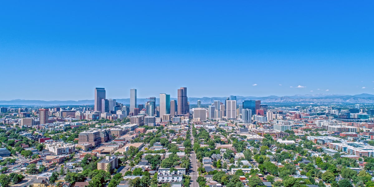 Aerial view of a major city skyline with a mountain range rising behind it