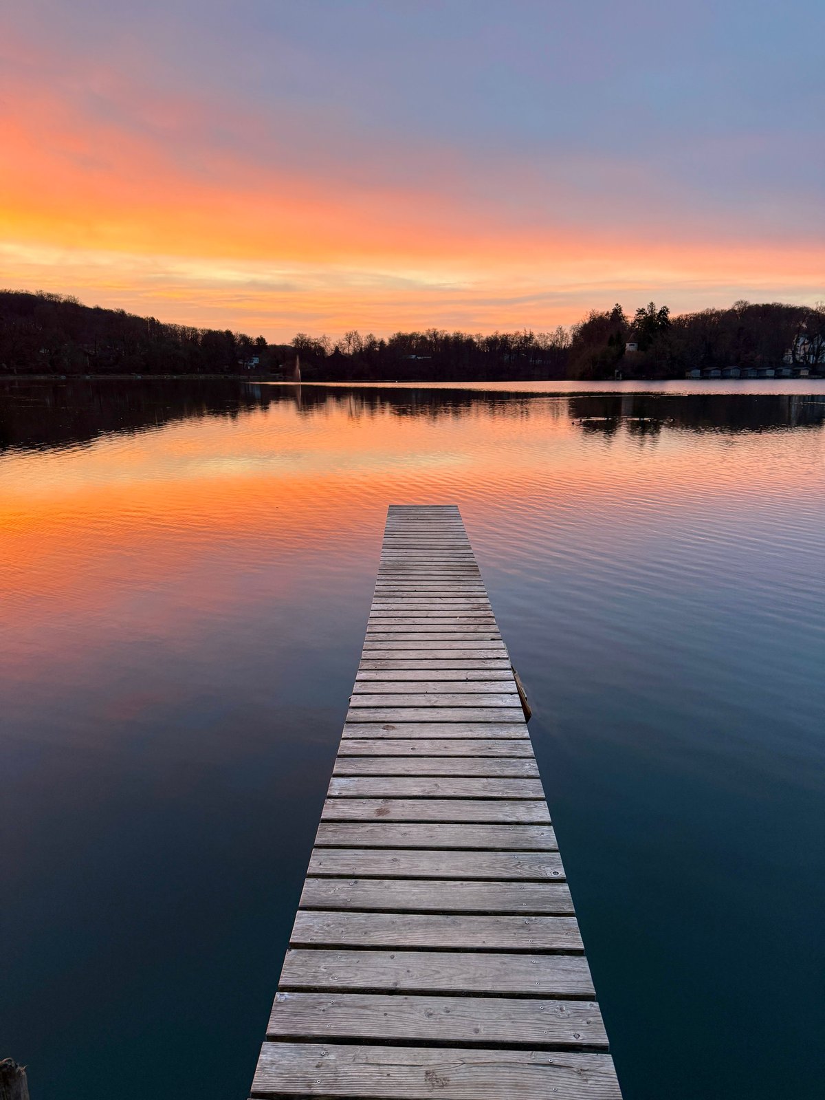 Sunset over Lake Stevens with a wooden pier and forested hillsides